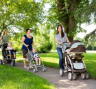 Happy mothers with their baby strollers walking together in park