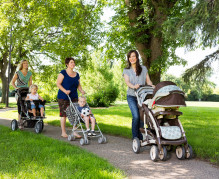 Happy mothers with their baby strollers walking together in park