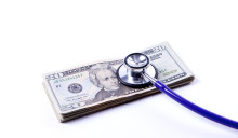 A conceptual image of a stack of twenty dollar bills with a stethoscope showing trouble.