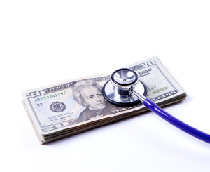 A conceptual image of a stack of twenty dollar bills with a stethoscope showing trouble.