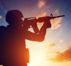 Soldier shooting with his weapon, rifle at sunset. War, army, military.